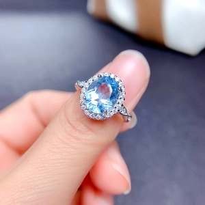 Detail of silver ring featuring oval blue topaz stone with a halo of small diamonds