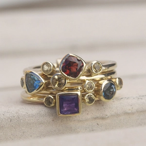 Set de anillos dorados apilables con gemas de colores y cortes geométricos variados