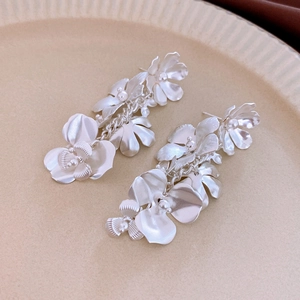 Macro detail of matte silver floral drop earrings with a metallic brushed texture on petals