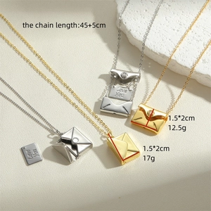 Gold envelope pendant necklace with 'Love You' engraved card on a textured stone background