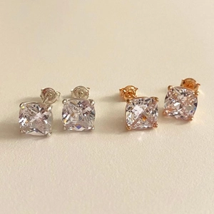 Detail of square zircon stud earrings in silver and rose gold with 4-prong setting