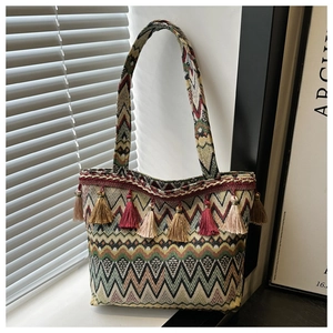 Detail of bohemian tote bag featuring geometric woven patterns and colorful fringe tassels