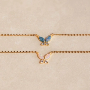 Detail of gold butterfly necklaces with blue and white opal stones and clear zircons