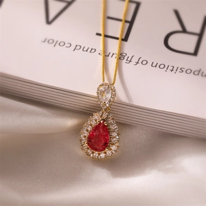 Detailed view of gold necklace with red teardrop gemstone and micro-pave crystals