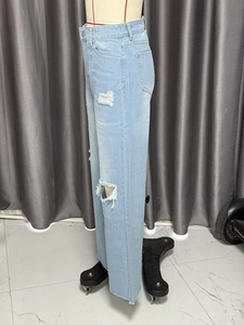 Detail of high waisted wide leg distressed jeans in light blue washed denim fabric