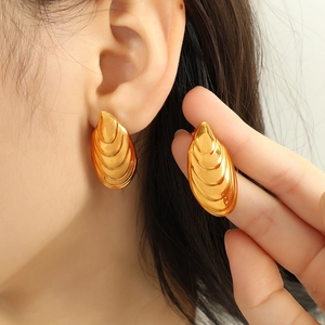 Fashion gold shell drop earrings with ribbed texture on model for size perspective
