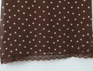 Détail du tissu marron à pois avec une bordure délicate en dentelle blanche sur l'ourlet
