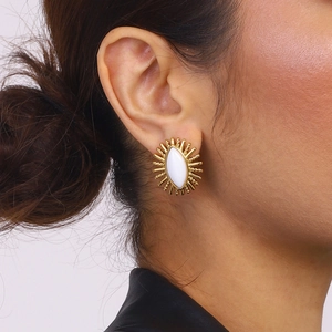 Detail of a vintage-style gold-plated earring with a white sunburst oval stone on model