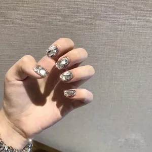 Detailed view of silver manicure nails with large sparkling rhinestones and crystal stones