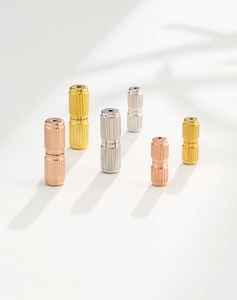 Detailed macro view of gold silver and rose gold knurled jewelry connectors on white background