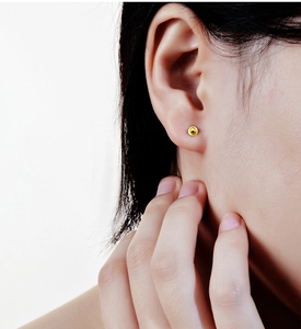 Macro shot of minimalist s925 silver screw back ball earring in polished gold finish