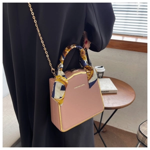 Pink trapezoid box bag with gold chain strap and decorative floral silk scarf handle