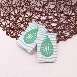 Detail of a greeting card featuring a green teardrop design and HI lettering on white cardstock