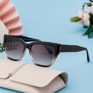 Fashionable oversized cat-eye sunglasses with gradient lenses on a beige leather case
