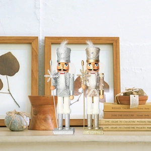 Close-up of gold and silver glitter nutcracker king dolls with scepters on a wooden shelf