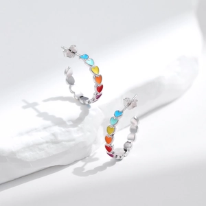 Rainbow heart stud earrings in s925 sterling silver on a white textured background