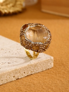 Macro detail of adjustable gold ring with champagne raw stone and crystal borders