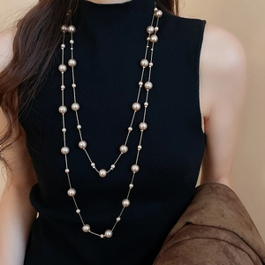 Close-up of elegant double-layer pearl necklace with golden chains on a black sweater