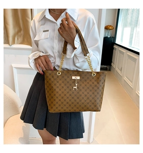 Dettaglio di una borsa tote marrone con catena dorata e ciondolo a forma di cervo