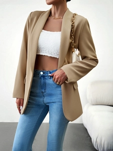 Détail d'un blazer beige ajusté avec un haut court texturé et un sac à main matelassé