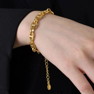 Polished 18k gold plated pig nose link bracelet on wrist with a black suit backdrop