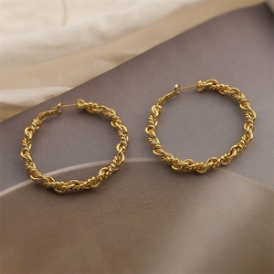 Macro detail of 18K gold plated hoop earrings with twist braid texture and metallic shine