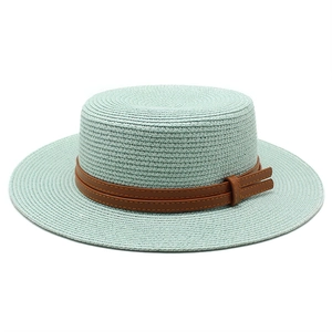 Detail of mint green boater straw hat featuring a double brown leather band and side buckle