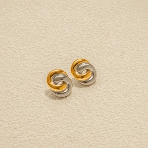 Details von ineinandergreifenden Edelstahl-Ohrringen in Gold und Silber mit Drehdesign