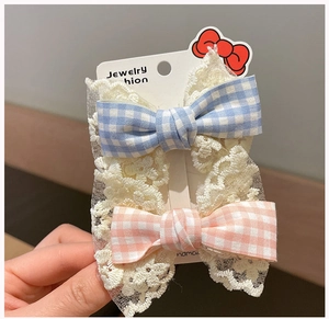Detailed view of handmade lace and plaid bow hair clips set on a display card
