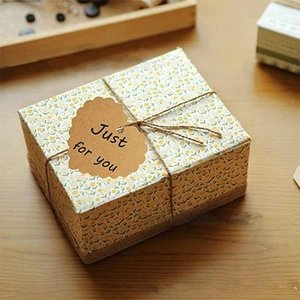 Square gift box with yellow floral paper, twine bow and heart-shaped kraft paper tag
