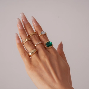 Detail of 6-piece vintage gold rings with green gemstone and pink crystals on hand