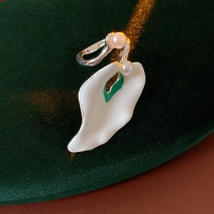 Detail of silver enamel flower petal earrings with white pearls on green velvet