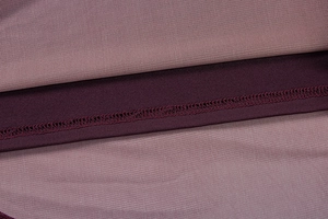 Vue détaillée des coutures overlock et de la jonction bicolore violette sur tissu en maille
