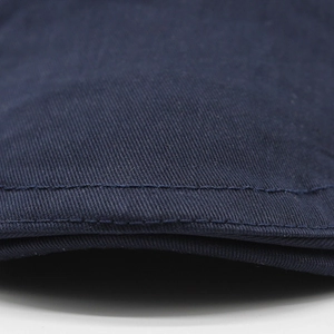 Detailed close-up of dark blue cotton newsboy cap brim with double row stitching