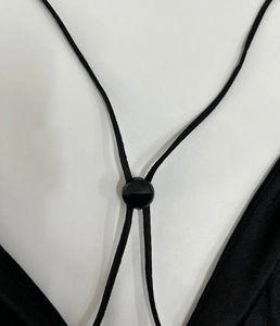 Detailed view of adjustable black mesh dress strap with round plastic slider buckle