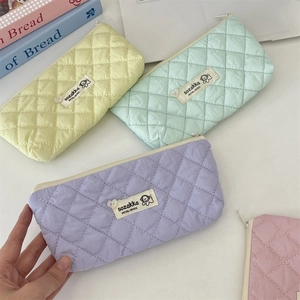 Close-up of quilted diamond pattern pencil cases in pastel colors with woven labels
