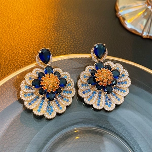 Detailed shot of vintage flower earrings with blue teardrop stones and gold finish