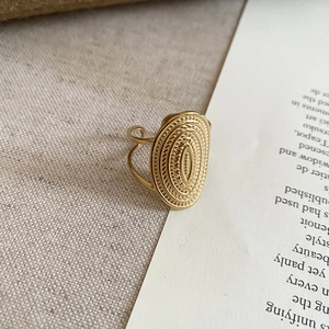 Detail of vintage gold open ring with embossed texture on textured linen background