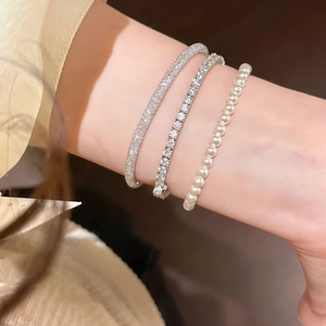 Close-up of sparkling cubic zirconia tennis bracelet and pearl wristband set on model
