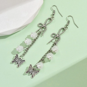 Detail of vintage silver drop earrings with white flower pendants and butterfly charms