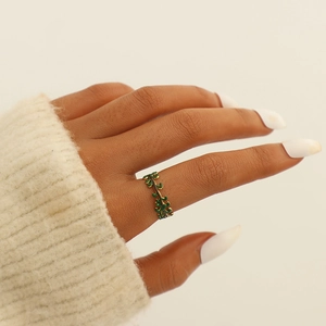 Close-up of gold-plated leaf ring with green enamel on a model's finger with soft knitwear