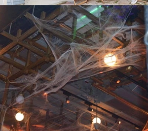 Close-up of realistic white cobweb decor draped over wooden ceiling for Halloween setups
