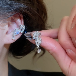 Macro shot of silver feather ear cuff with sparkling zircon stones worn on the ear