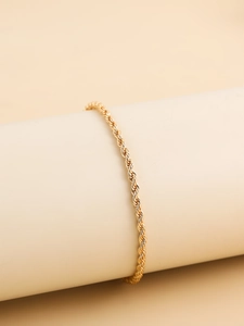 Detailed macro view of the golden twisted rope chain bracelet on a minimalist display stand