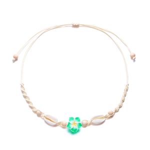 Detail der gewebten Strandkette mit grüner Frangipani-Blüte und natürlichen Muscheln