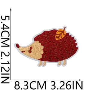 Detailed close-up of hedgehog embroidery patch with autumn leaf on white background