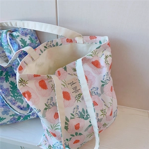 Détail de sacs fourre-tout en coton blanc avec imprimés floraux et étiquette décorative