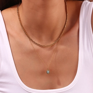 Detail of layered gold cuban chain and light blue oval gemstone pendant on model