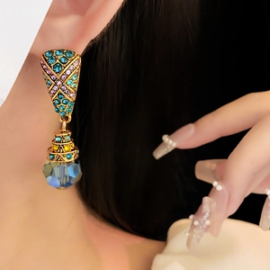 Close-up of vintage earrings with blue and purple crystals on a gold metal setting