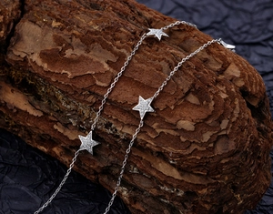 Macro shot of S925 sterling silver star necklace with sparkling zircon on natural bark